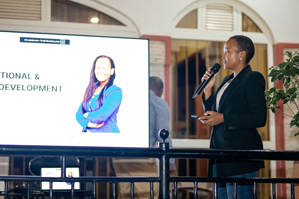 A presenter speaks beside a screen showing her slides